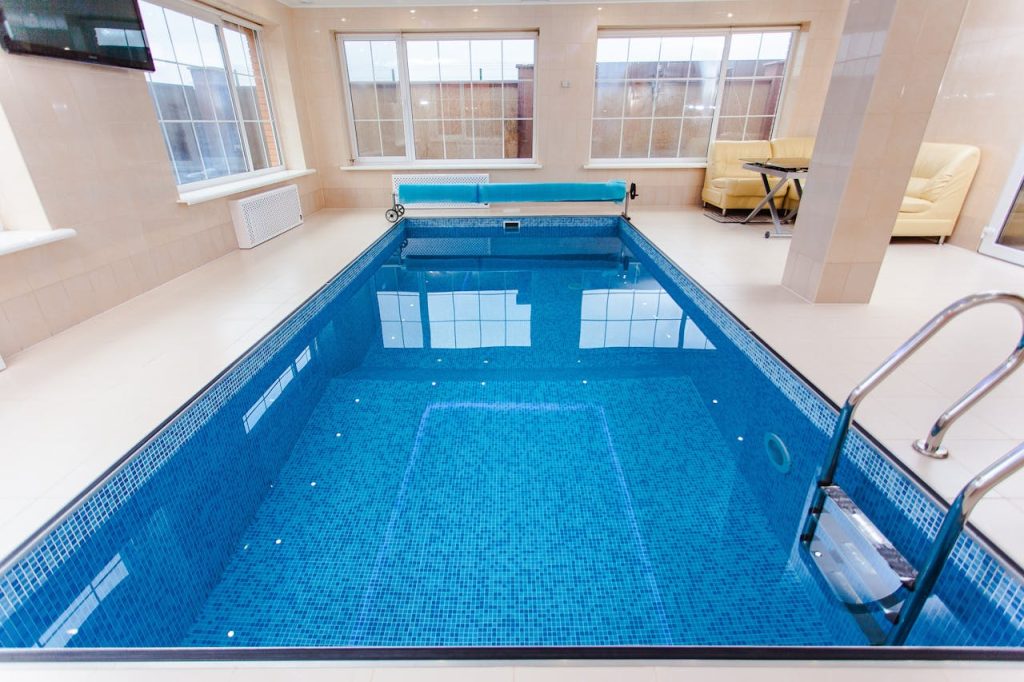 Bright indoor swimming pool with luxury seating and large windows.